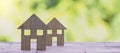 Two wooden house figurines on a table with a blurred background