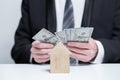 Two wooden houses and us money dollars in businesman hands. Byuing property, insurance concept Royalty Free Stock Photo