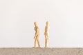 Two wooden human figures standing on a block with their backs to each other