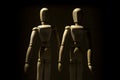 Two wooden mannequin models on dark background