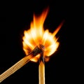 Two wooden matches caught in the instant of ignition, with one transferring its flame Royalty Free Stock Photo