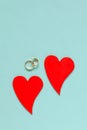 Two wooden red hearts and wedding rings on blue background Royalty Free Stock Photo