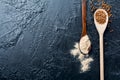 Two wooden spoons with buckwheat and flour opposite each other on a black background. Selective focus. Top view. Place for text