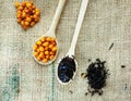 Two wooden spoons with vitaminic healthy sea buckthorn berries and black tea over sackcloth background. cooking, Royalty Free Stock Photo