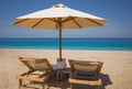 Two wooden sun loungers and sun umbrella on sandy beach with turquoise sea. Holidays on islands of Greece Royalty Free Stock Photo