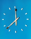 Two wooden toothbrushes form the hands of a clock with white rectangular pieces of gum marking the hours on a blue background Royalty Free Stock Photo