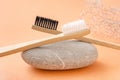 Two wooden toothbrushes on stone on pastel coral background Royalty Free Stock Photo