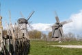 Two wooden windmills with a wooden fence on a blue sky background Royalty Free Stock Photo