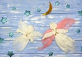 Two woolen flying angel dolls, stars and lunar month on blue wooden background