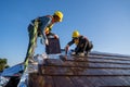 Two work construction worker wearing safety height equipment harness belt during working and install new ceramic tile roof with Royalty Free Stock Photo