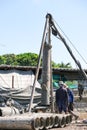 Two worker man working piling equipment. Building house by use three legs crane. Many pile steel tube for digging Royalty Free Stock Photo