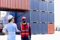 Two worker wearing safety helmet shaking hands at logistic shipping cargo containers yard. African American engineer man having Royalty Free Stock Photo