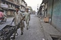 Two workers carrying a motorized wheelbarrow on a well-known street in Islamabad where parts of cars of all kinds are sold.