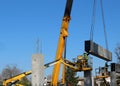 Two workers on two cherry pickers install a prefab concrete slab, lifted by a telescopic crane, on the new wall of the building u Royalty Free Stock Photo