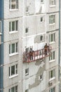 Two workers in construction cradle on metal cables repairing vertical iwall surface on block of flats house