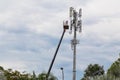 Two workers on crane installing mobile network communication ant
