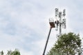 Two workers on crane installing mobile network communication ant