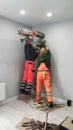 Two workers drill a hole in wall, diamond drilling. Preparation for installation of Heat Exchangers - Recuperator Royalty Free Stock Photo