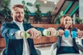 Two workers exercising with dumbbells at desk. Royalty Free Stock Photo