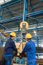 Two workers handling heavy loading lifted by crane