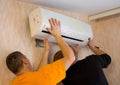 Two workers install the air conditioner in the apartment