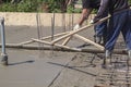 two workers leveling fresh concrete slab with a special wooden w Royalty Free Stock Photo