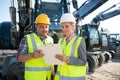 Two workers in open cast mine standing in front of heavy machinery Royalty Free Stock Photo