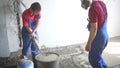 Two workers in overalls prepare mixture for