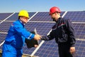 Two workers shake hands in front of the solar power plant Royalty Free Stock Photo