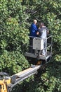 Two workers on a small crane lift repairing a street light