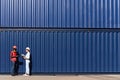 Two workers wear safety vest and helmet discus at logistic shipping cargo container yard workplace. African American engineer man