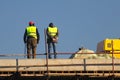 Two Workers in yellow at the construction site ower blue sky Royalty Free Stock Photo