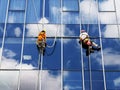 Two working climbers are on a glass wall of a high-rise building Royalty Free Stock Photo