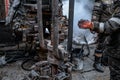 Two working drillers in a uniform, in a helmet and goggles, install drill pipes after lifting them from an oil well Royalty Free Stock Photo