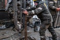 Two working drillers in a uniform, in a helmet and goggles, install drill pipes after lifting them from an oil well Royalty Free Stock Photo