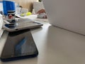 Two working touchscreen mobile phones, smartphones lie on the table in the office with stationery, a stapler, a seal and a laptop