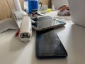 Two working touchscreen mobile phones, smartphones lie on the table in the office with stationery, a stapler, a seal and a laptop