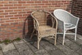 Two worn wicker chairs standing by a surrounded wall Royalty Free Stock Photo