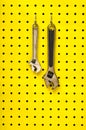 Two wrenches hang from hooks on yellow pegboard Royalty Free Stock Photo