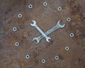 Two wrenches and nuts in the shape of a clock on an old rusty metal surface. Spanners and nuts laid out in the form of a clock on