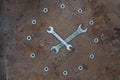 Two wrenches and nuts in the shape of a clock on an old rusty metal surface. Spanners and nuts laid out in the form of a clock on