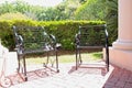 Two wrought iron chairs sit on a patio overlooking beautifully landscaped garden