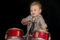 Two year caucasian boy is Playing Drum Set Isolated on Black Background