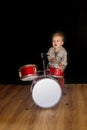 Two year caucasian boy is Playing Drum Set on Black Background