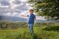 A two-year-old boy in a blue T-shirt and jeans stands on top of a mountain. Ukrainian Carpathians. Lonely. Smiling boy.