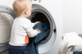 Two year old child doing household chores. Loading washing machine Royalty Free Stock Photo