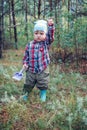 Two year old child in rubber boots and a shovel in the forest Royalty Free Stock Photo