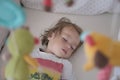 A two-year-old child sleeps peacefully in his crib.