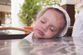 Two-year-old girl asleep at a table in the street cafe Royalty Free Stock Photo