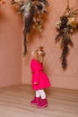 Two-year-old girl in bright pink dress pink shoes looks at vases with flowers Royalty Free Stock Photo